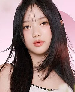 Hanni (NewJeans) wearing muted autumn ensembles with velvety textures and gentle warmth, showcasing apricot, sage, muted teal, warm beige, and berry from the Soft Autumn palette.