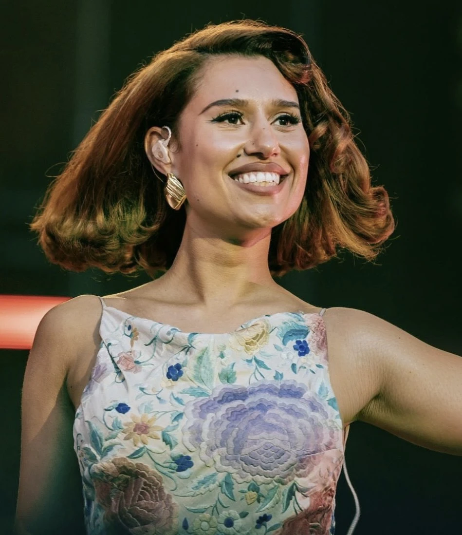 RAYE wearing luminous spring outfits with juicy warm hues, showcasing papaya orange, sunny marigold, aqua turquoise, creamy ivory, and rose gold from the Warm Spring palette.